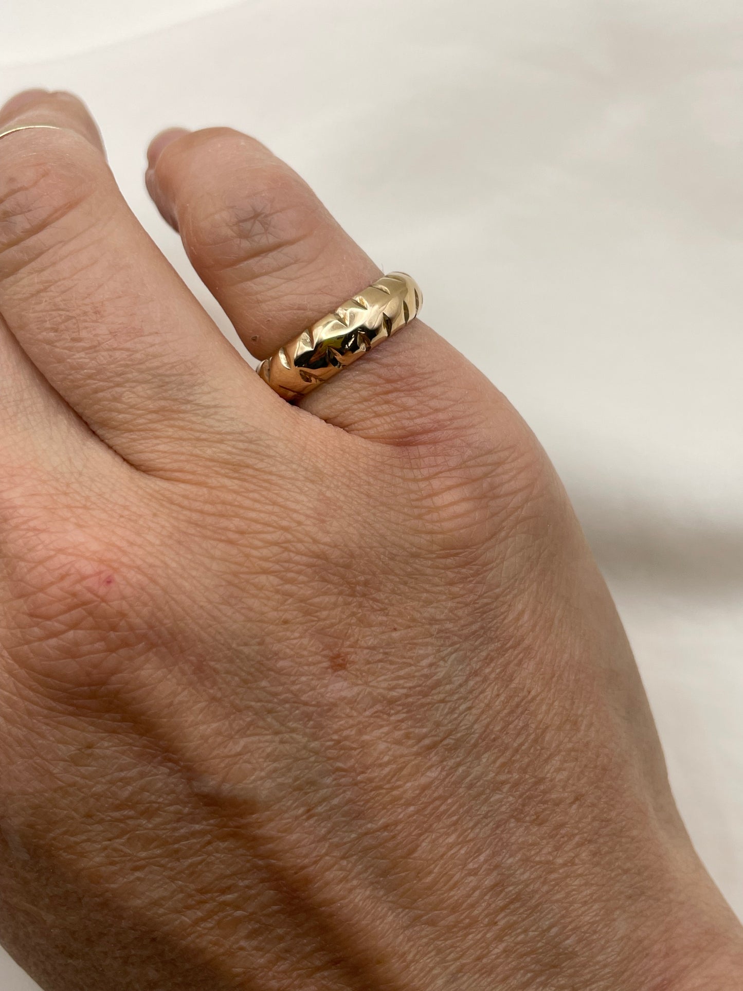 Gold ring on a person's finger against a plain background